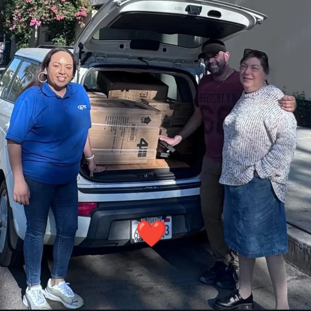Italia, Craig, and Pam loading donated hygiene items from the Dr. Simi Foundation and Immaculate Heart Community into a car in Los Angeles